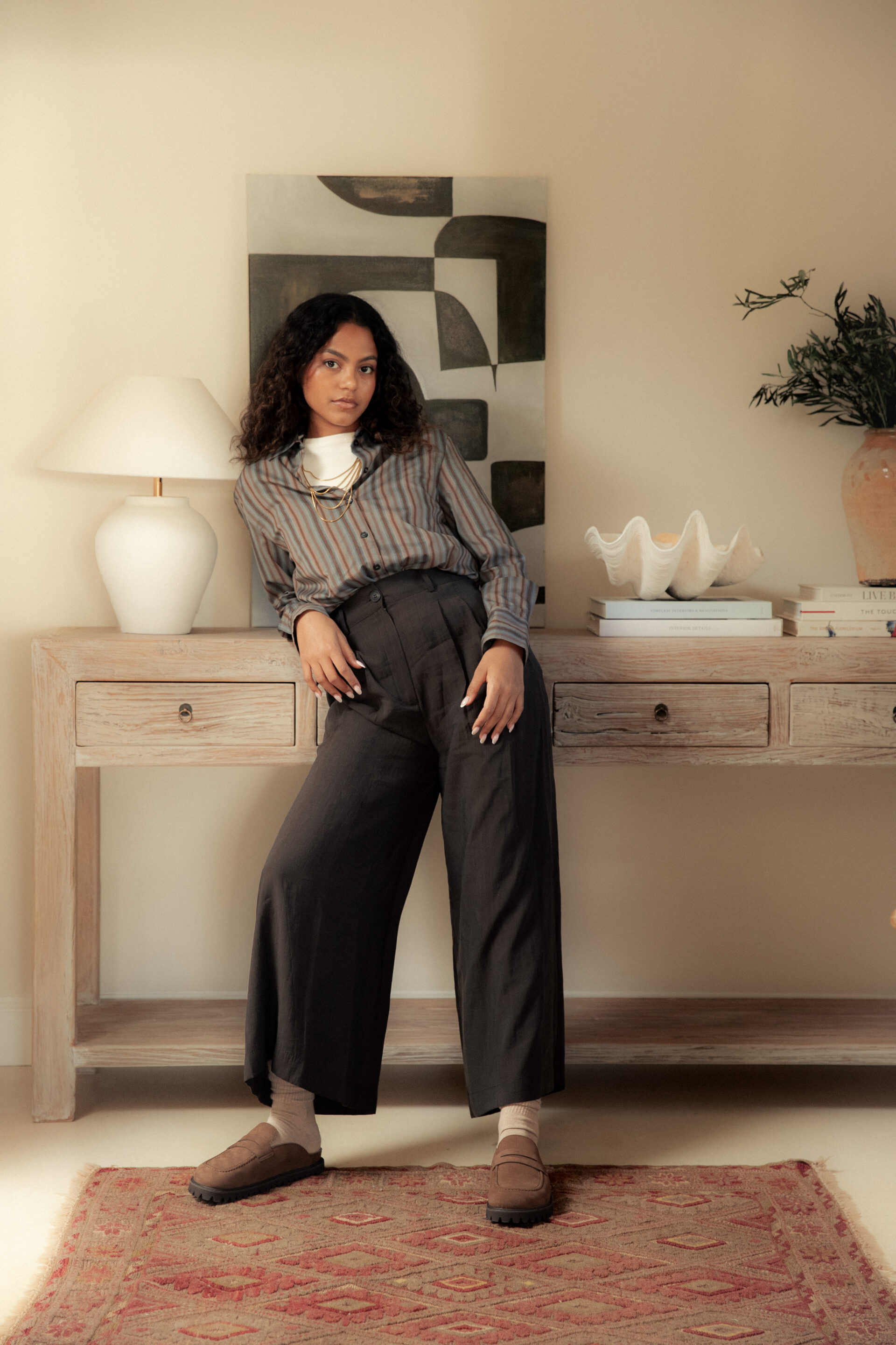 Chica posando en una cómoda mientras el fotógrafo le toma una foto