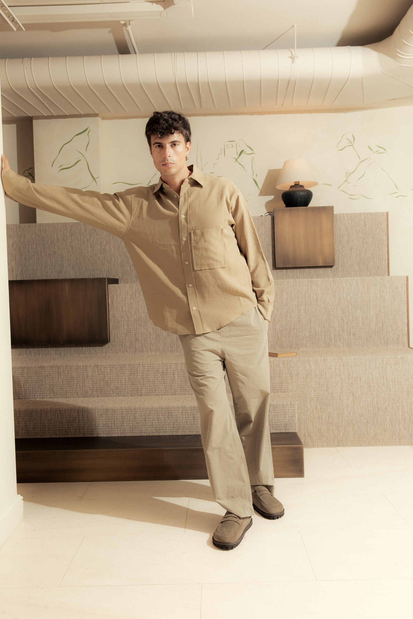Chico posando apoyándose en la pared mientras el fotógrafo le toma una fotografía
