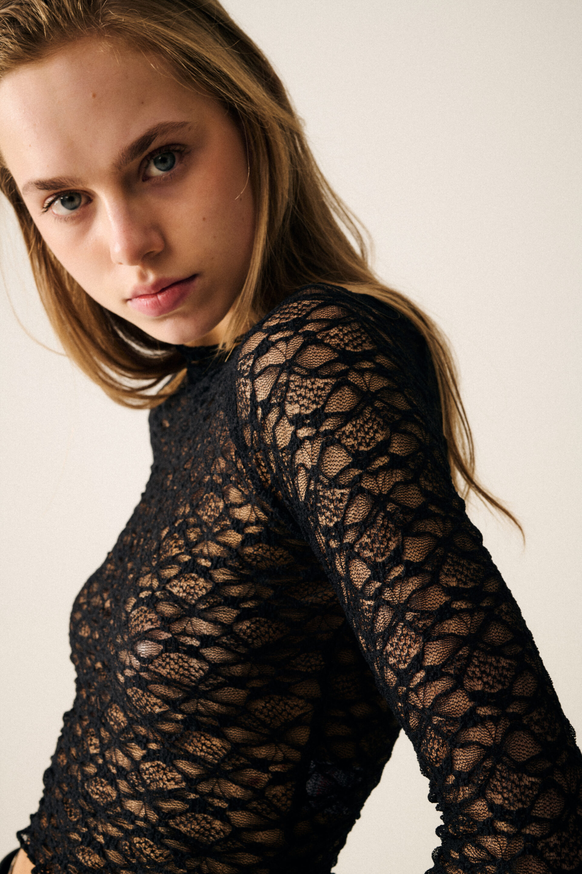 Chica con una camiseta de encaje posando mientras el fotógrafo le toma una foto