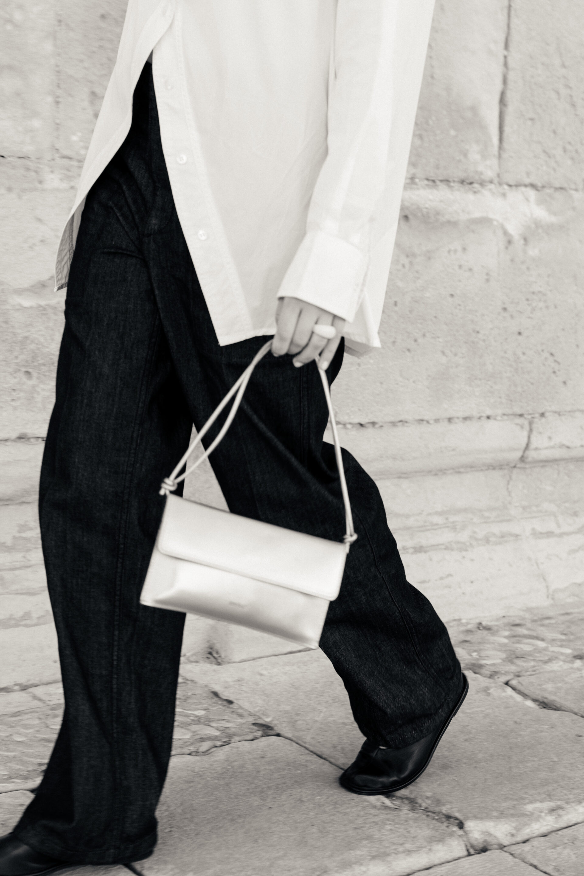 Chica andando con el bolso plateado. Fotógrafo tomando la fotografía en blanco y negro