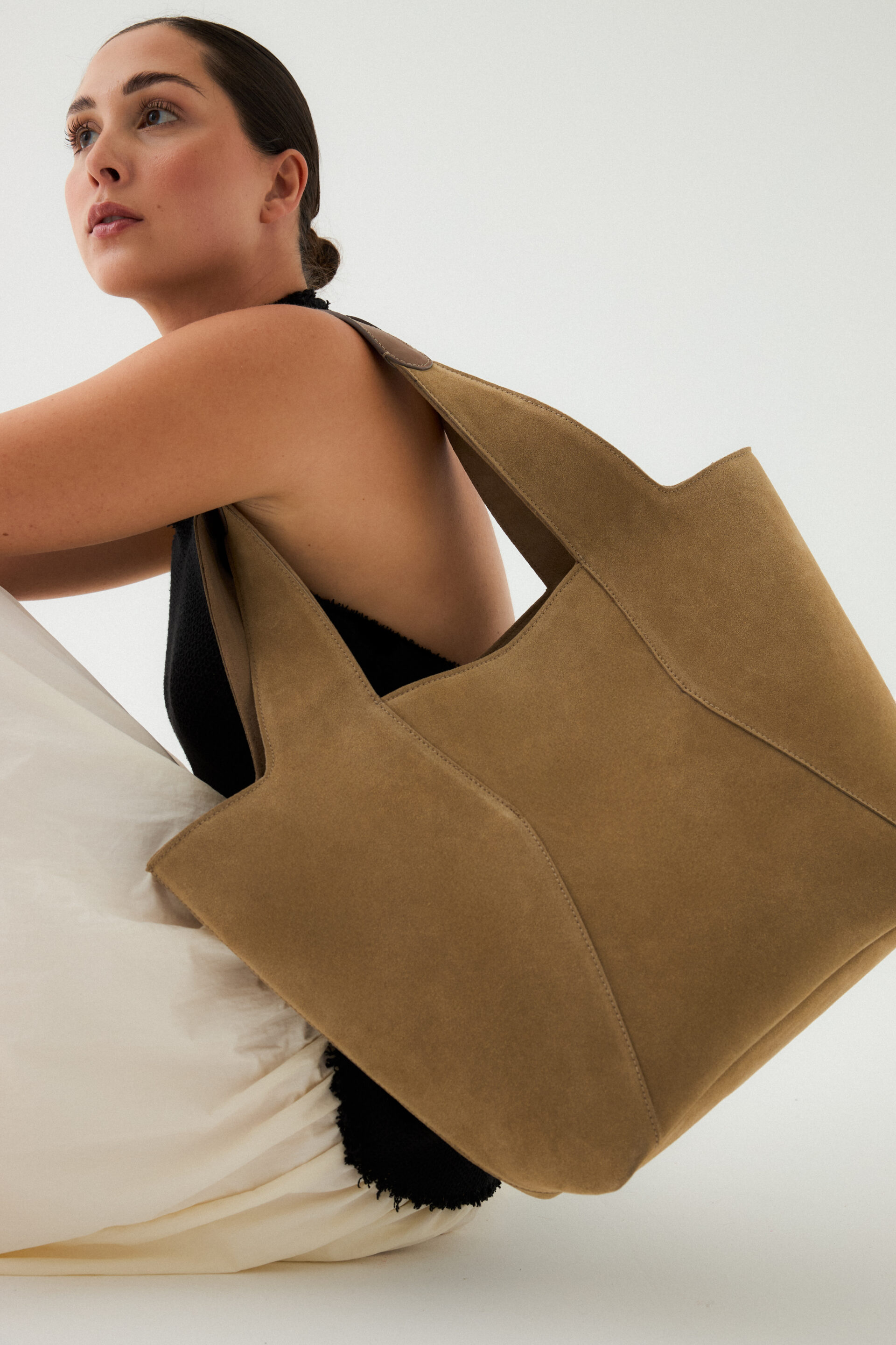 Chica sentada con un bolso grande marrón mientras el fotógrafo le toma una foto