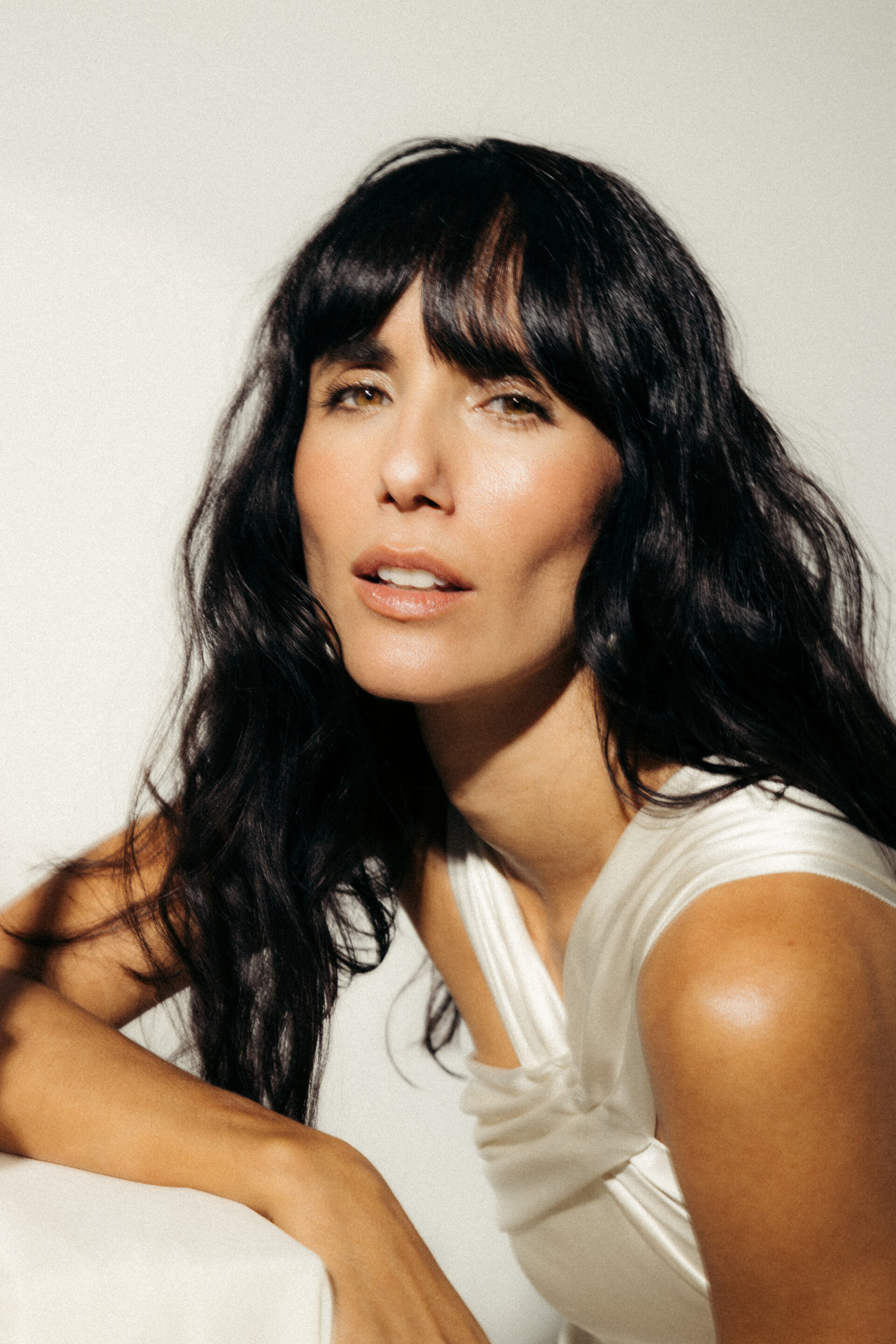 Chica con un vestido cruzado con el pelo recogido mientras el fotógrafo le toma una foto