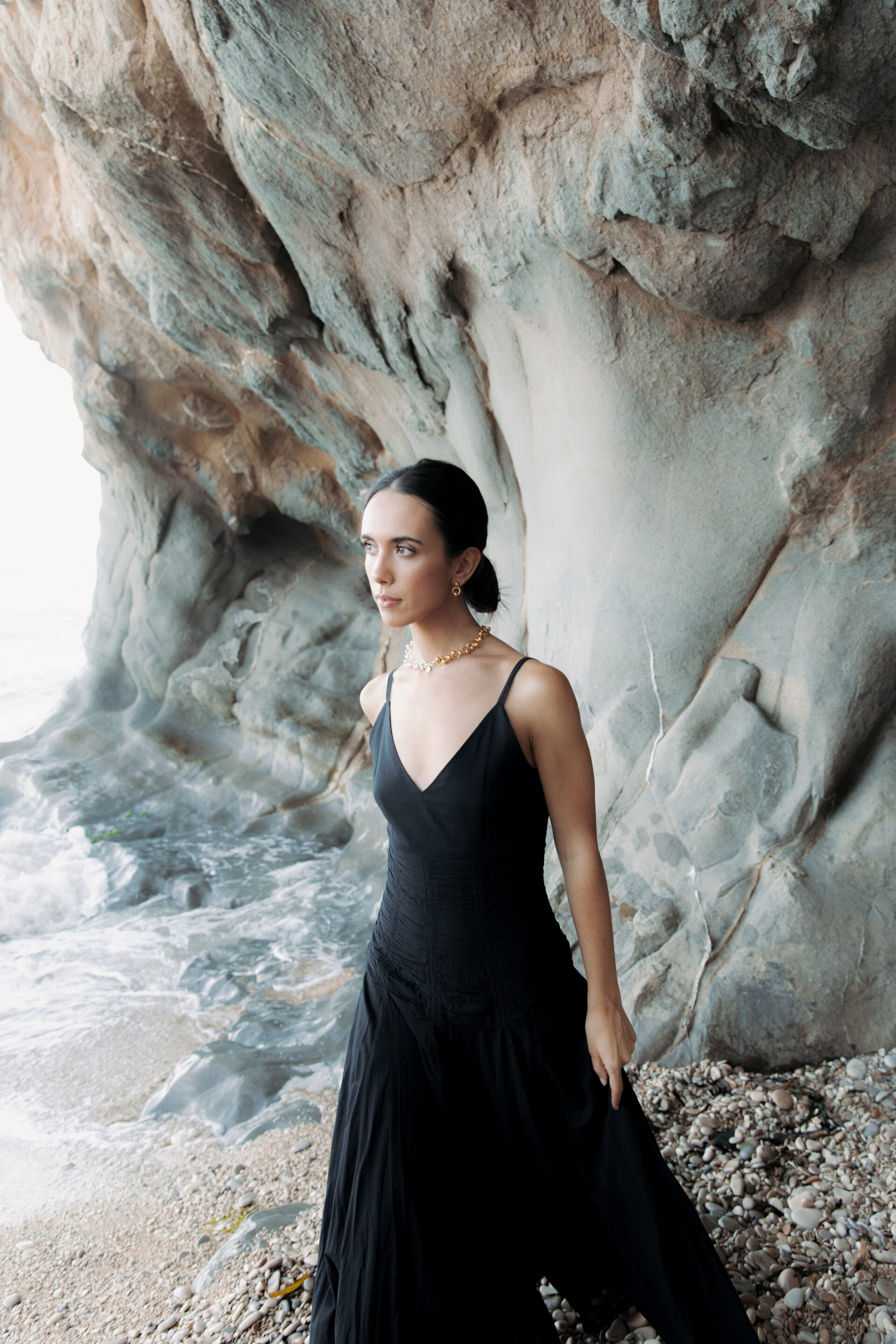 Chica con un vestido negro posando mientras fotógrafo le toma una fotografía