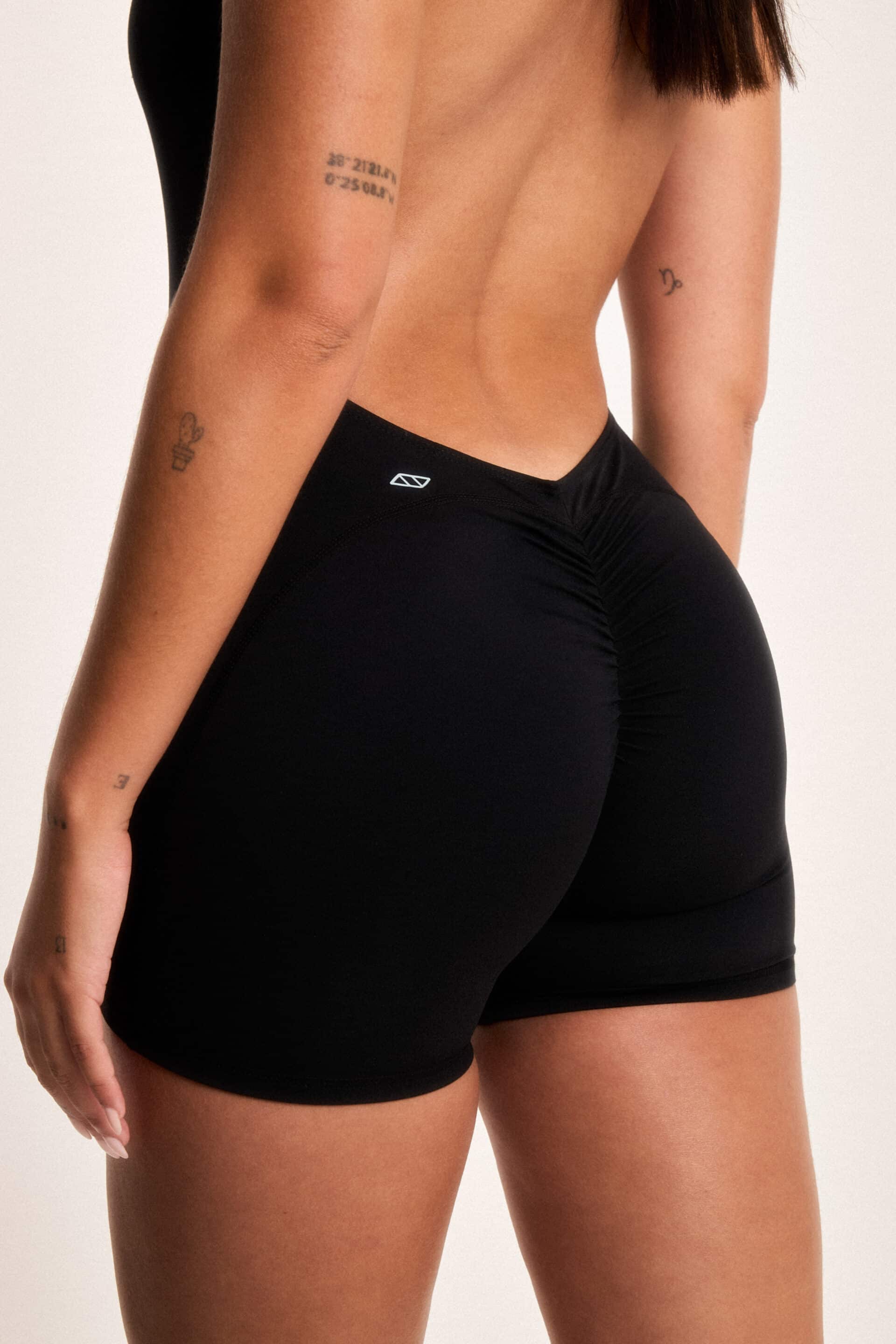 Chica con conjunto deportivo negro de la marca PBS posando de espaldas mientras el fotógrafo le toma una foto