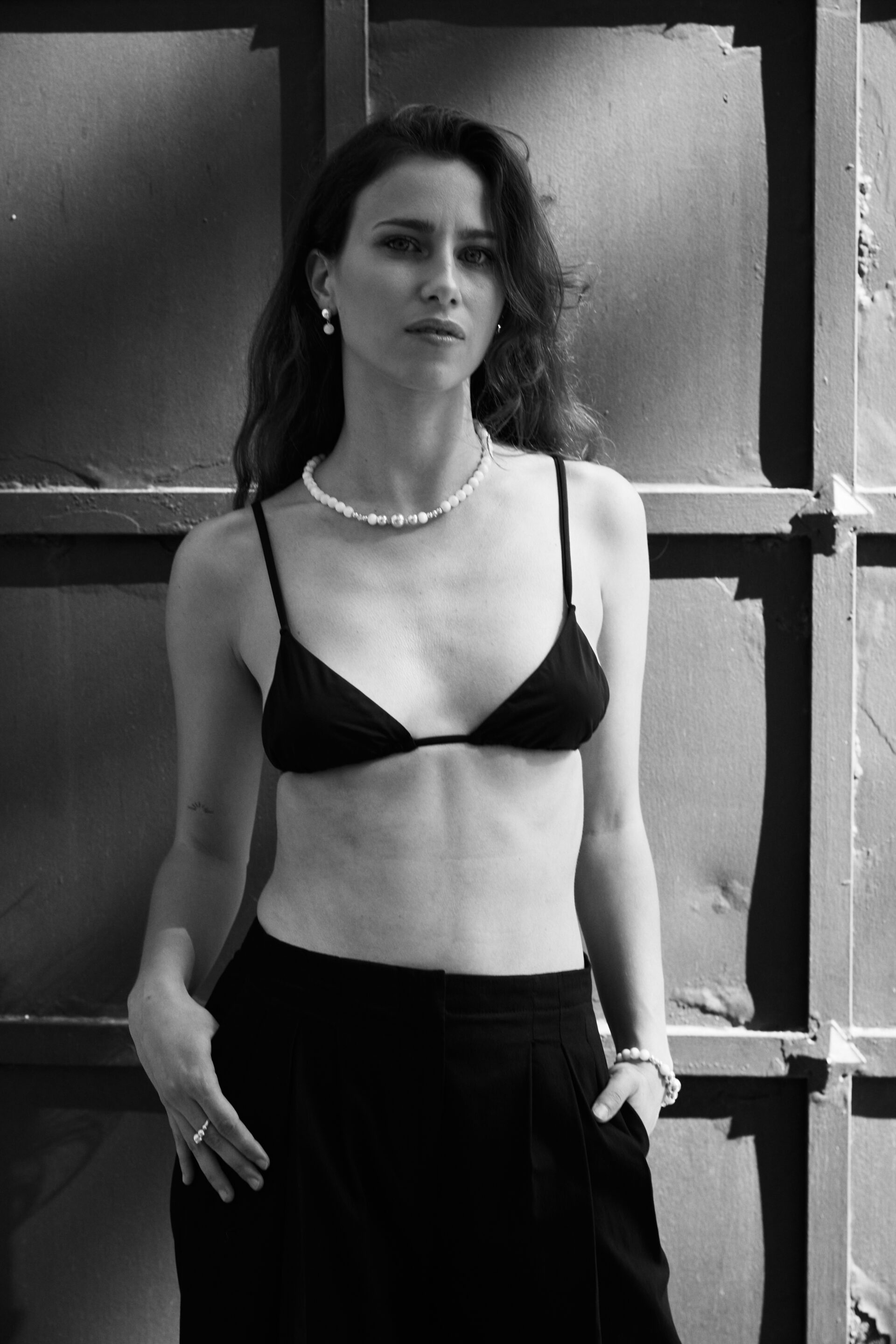 Chica con top negro posando de frente mientras fotógrafo le toma una fotografía en blanco y negro