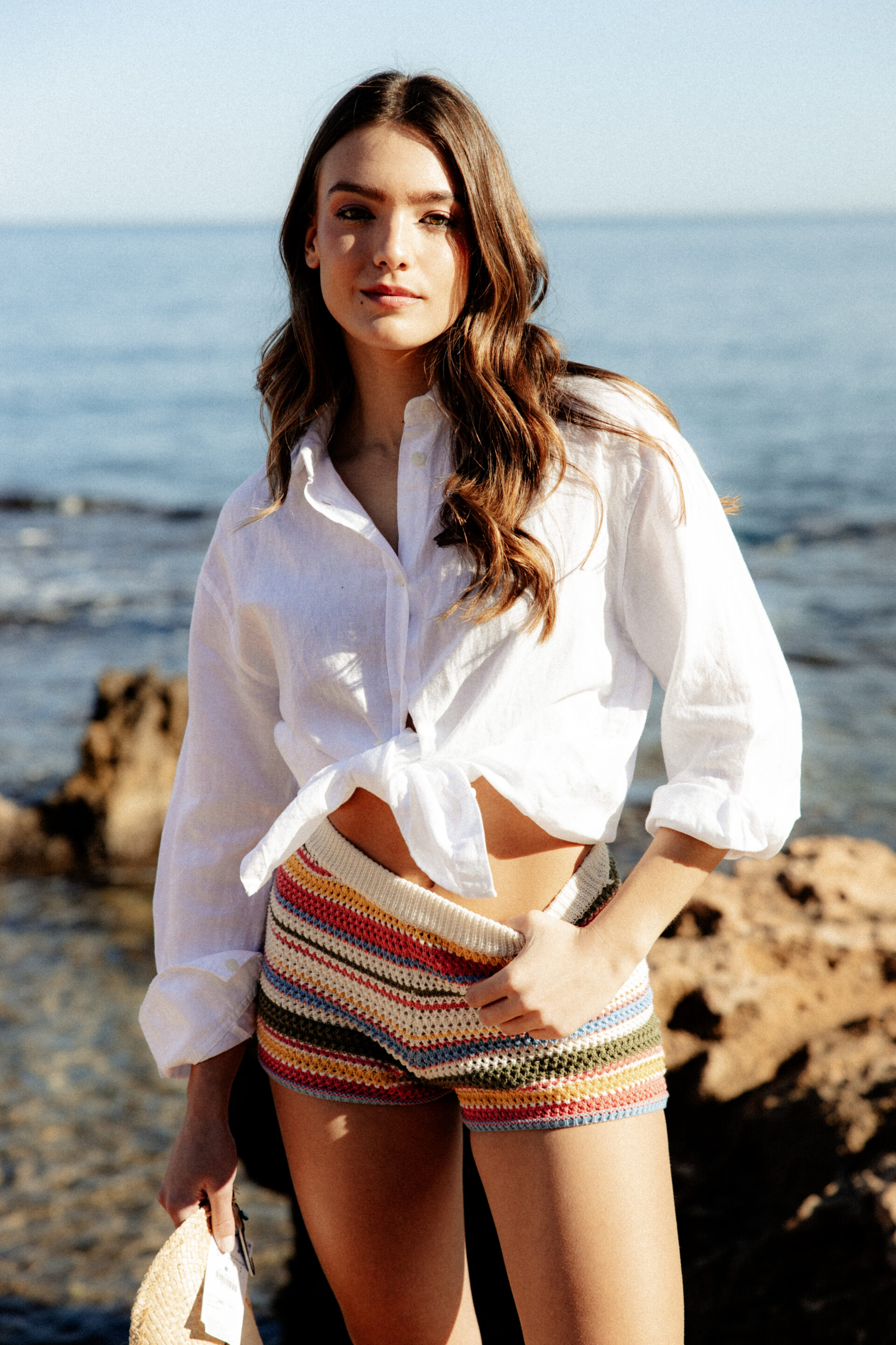 Chica posando en la playa con un sombrero vaquero mientras el fotógrafo le toma una fotografía