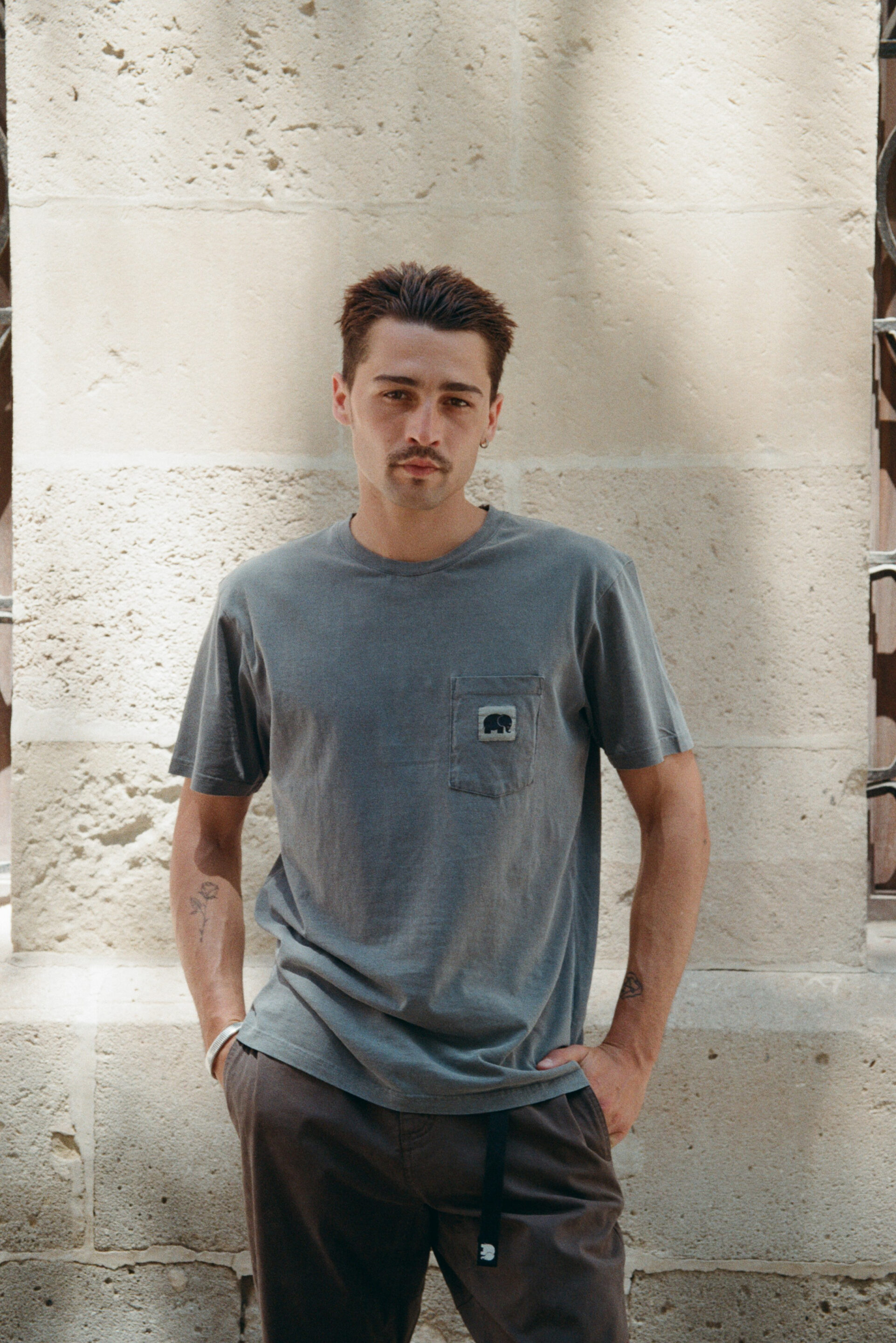 Chico posando con camiseta gris mientras el fotógrafo le toma una foto