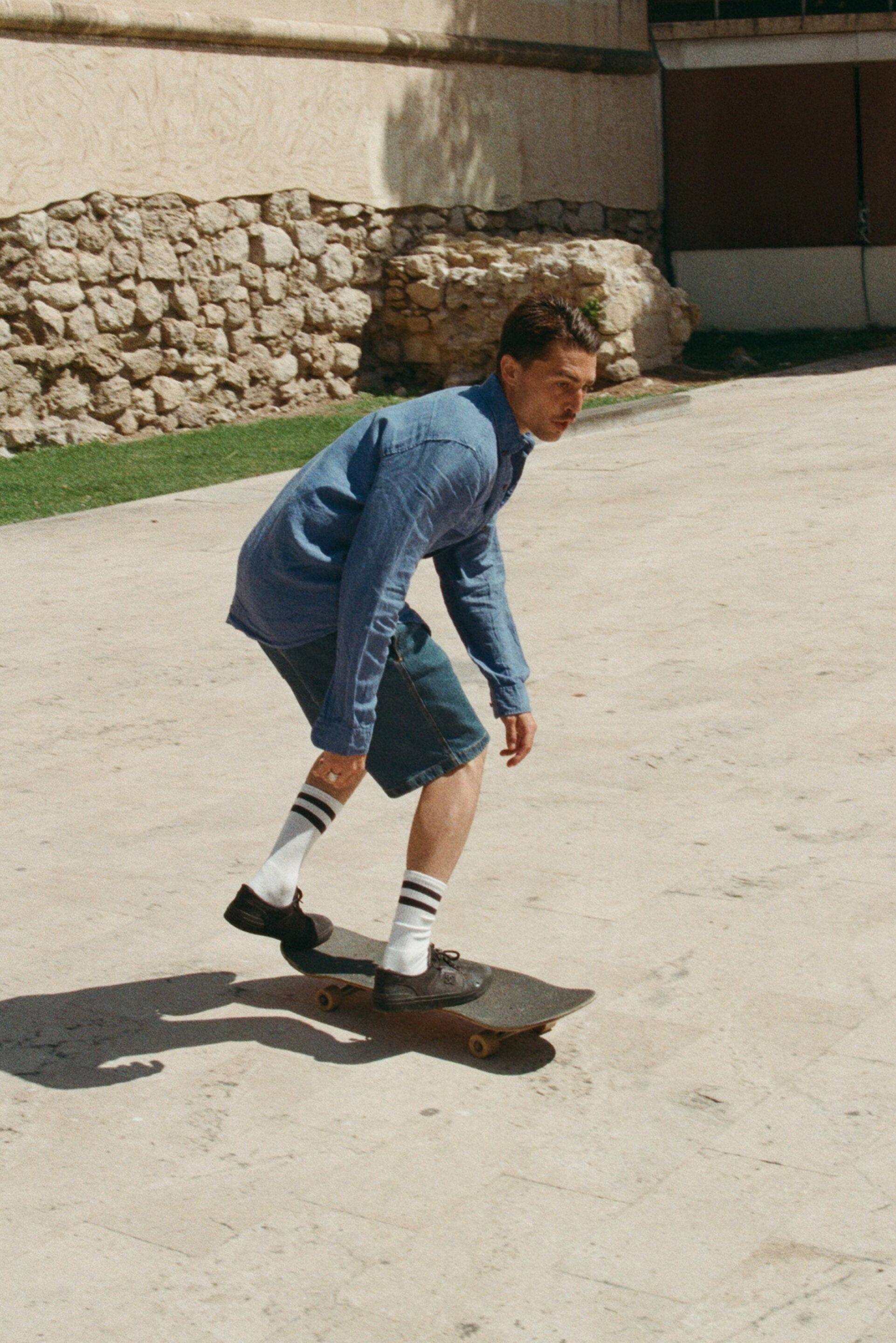 Fotógrafo tomando una foto a un chico con un conjunto vaquero que esta montando en un skate