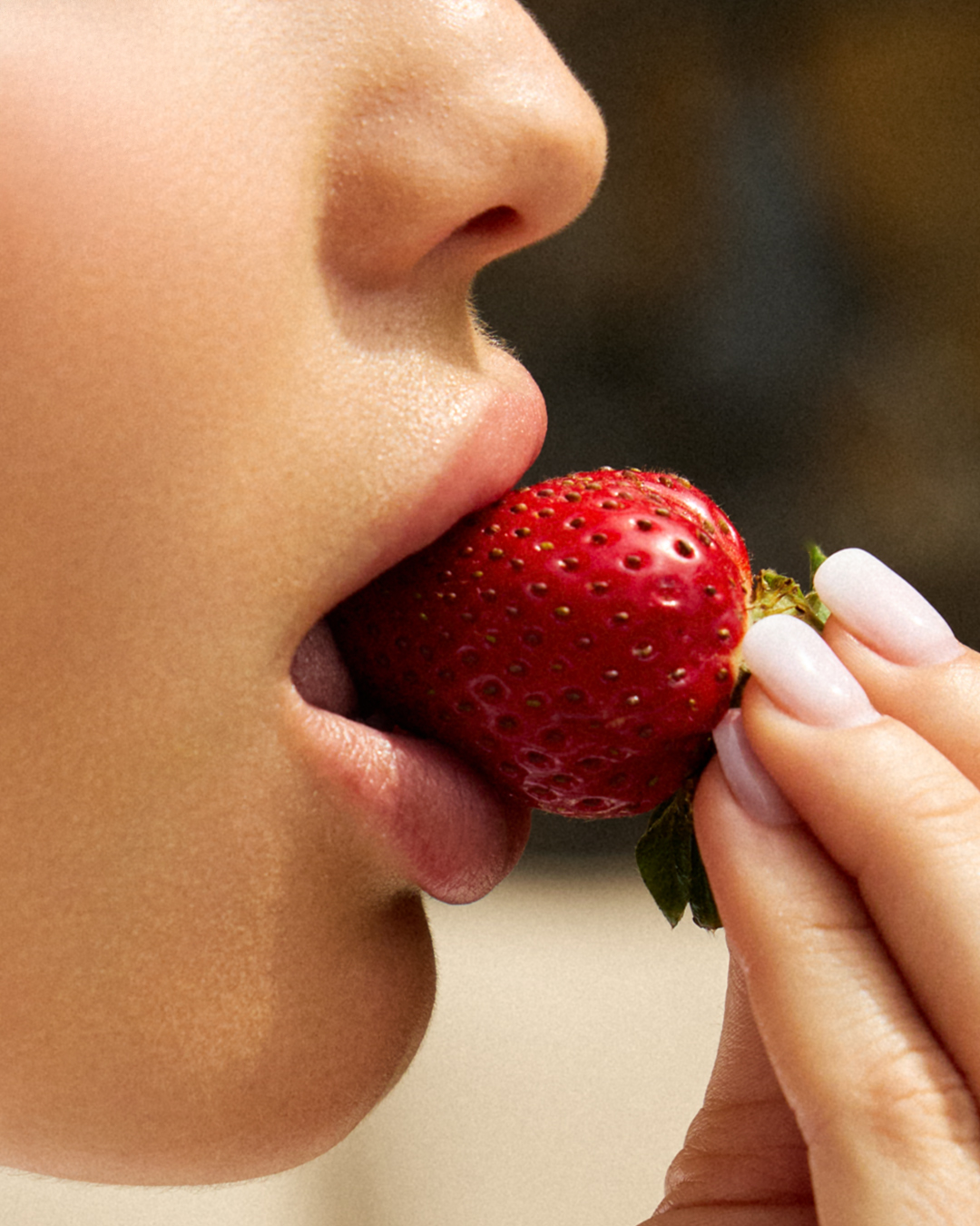 Chica comiéndose una fresa mientras fotógrafo le toma una foto
